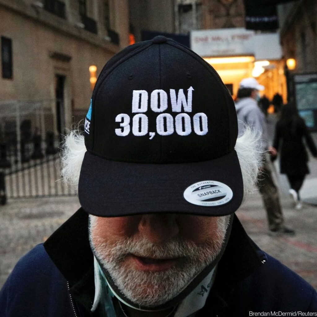 Trader Peter Tuchman wears a “DOW 30,000” hat as he greets friends outside the N...